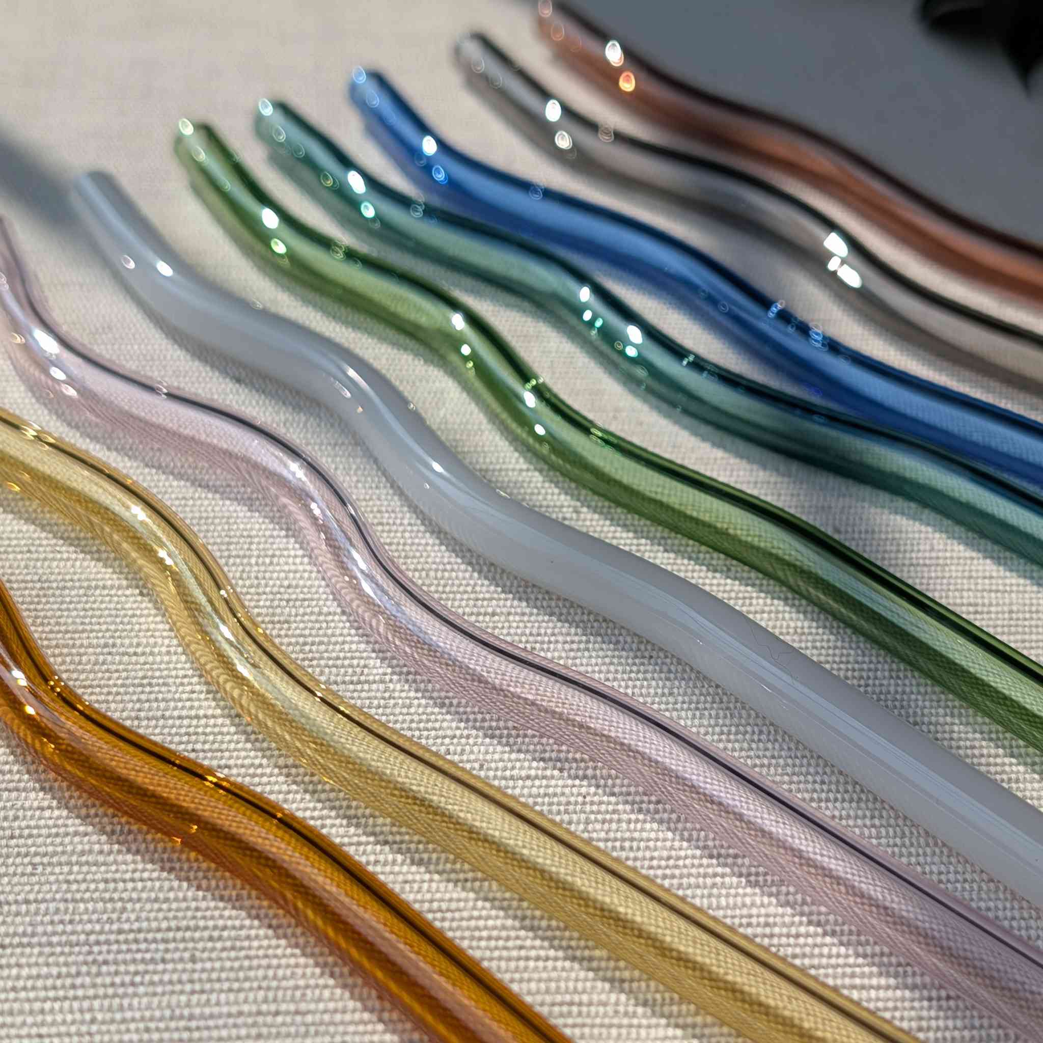 Set of colorful wavy glass straws in pastel and earthy tones, reusable and eco-friendly