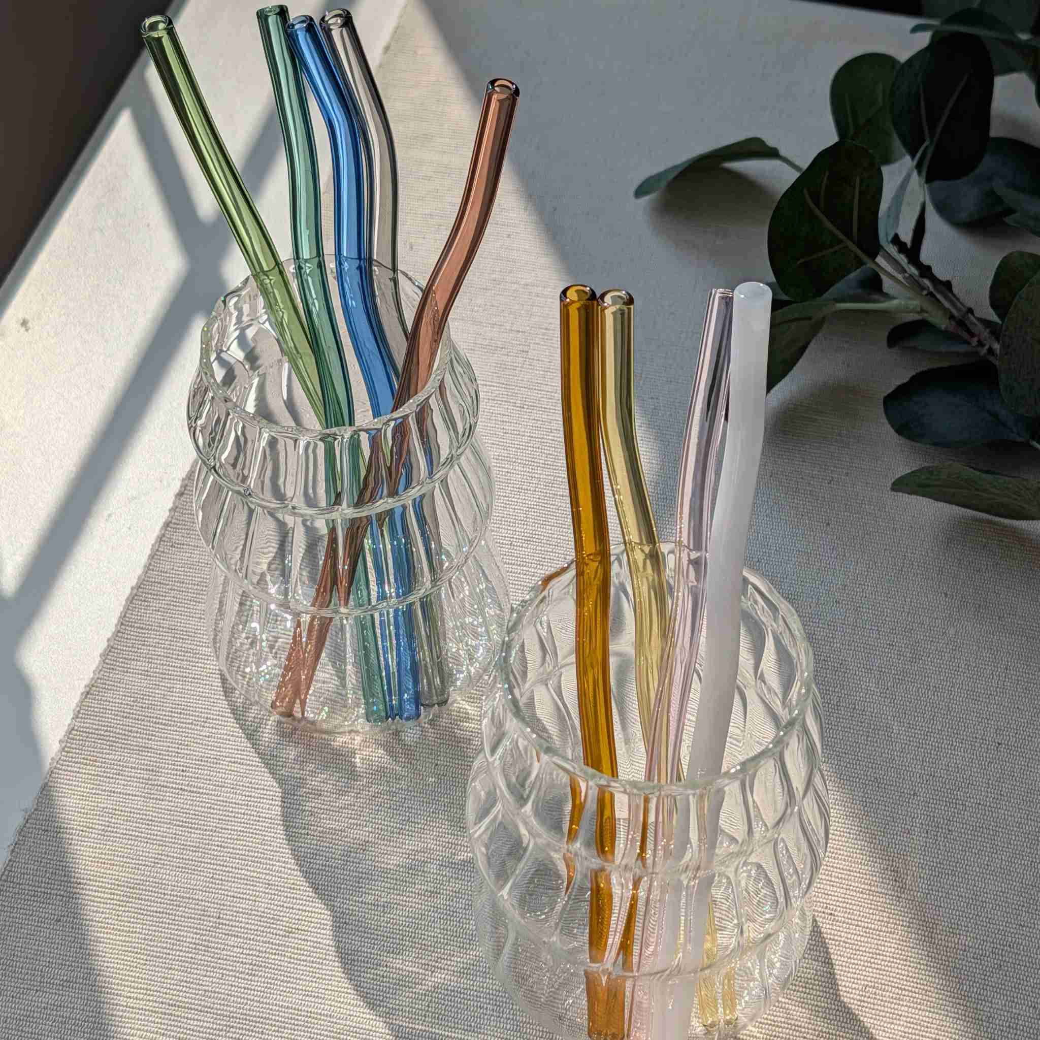 Set of colorful wavy glass straws in pastel and earthy tones, reusable and eco-friendly