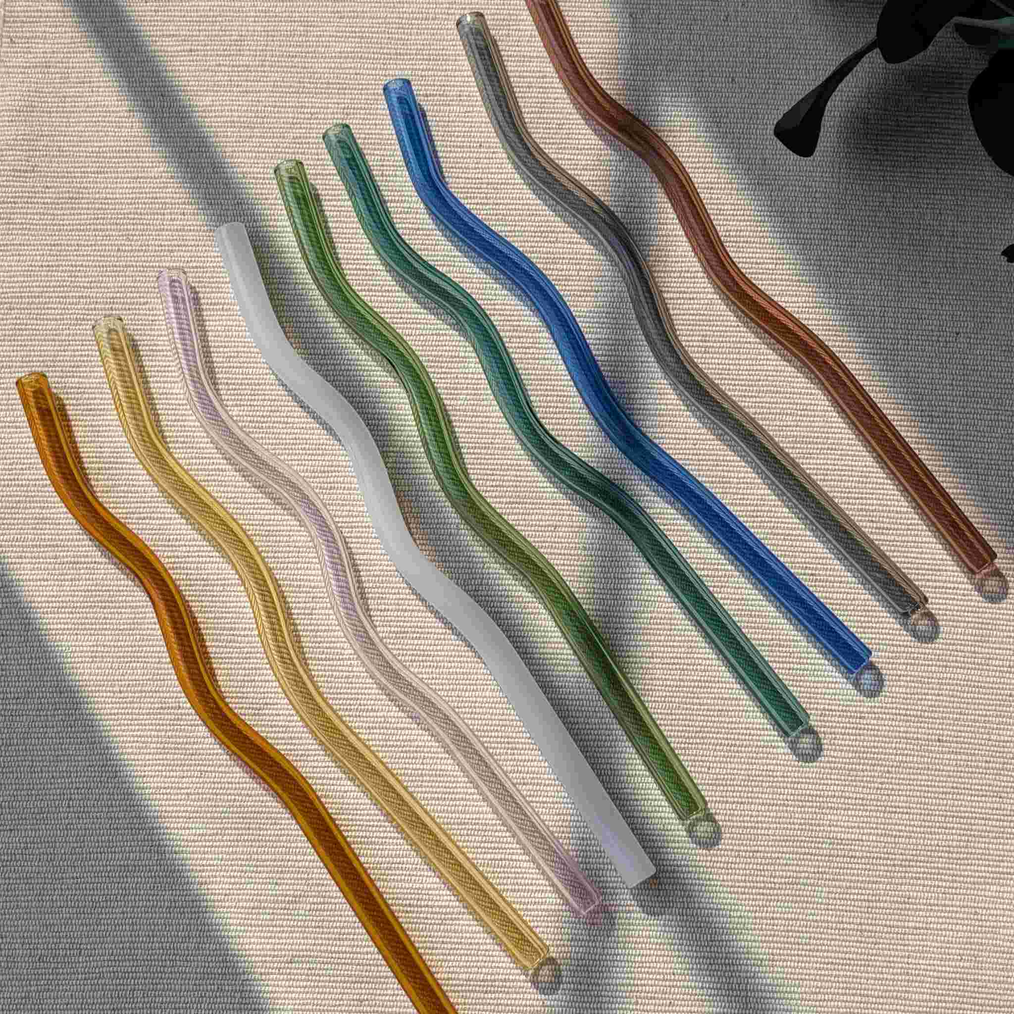 Set of colorful wavy glass straws in pastel and earthy tones, reusable and eco-friendly