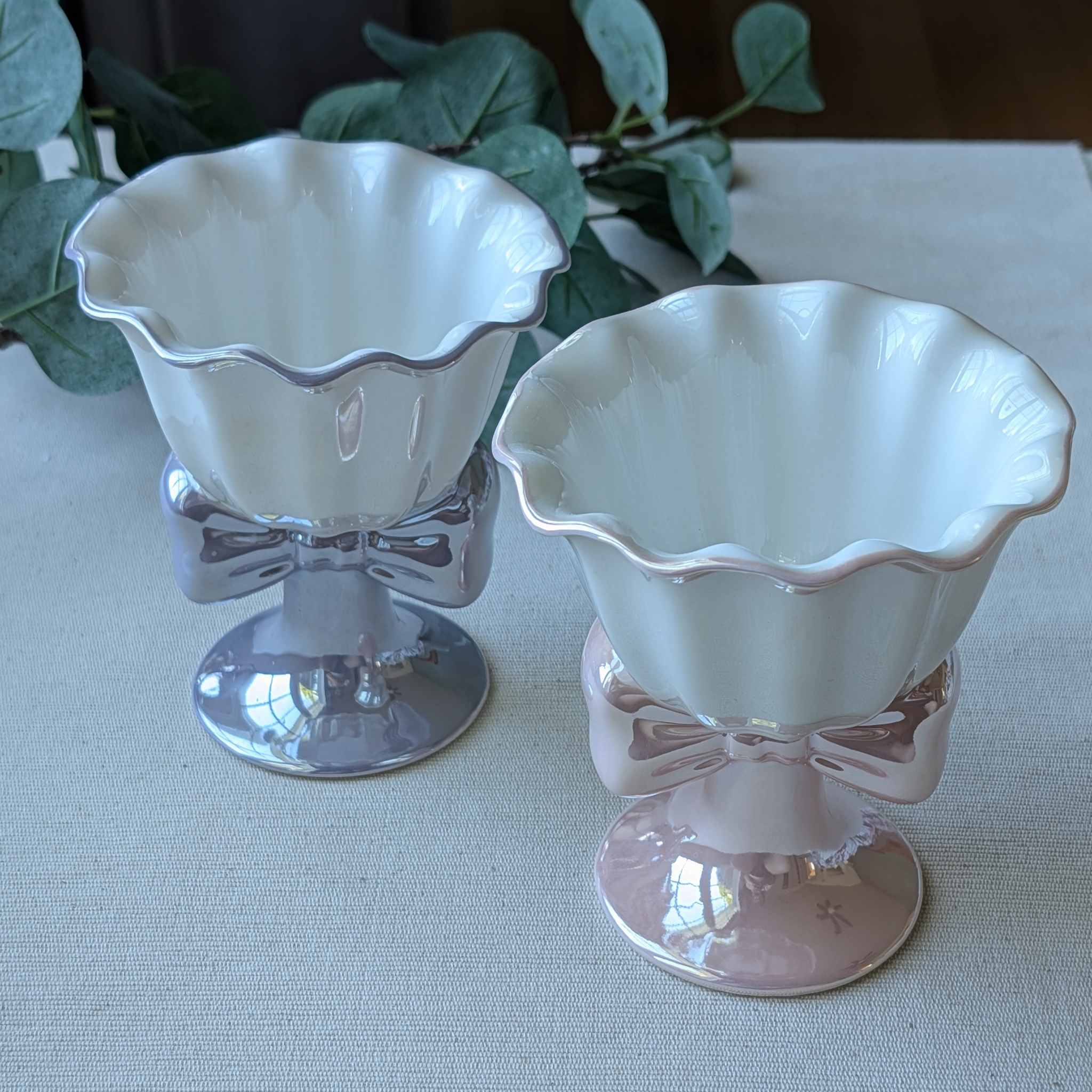 Elegant ceramic dessert cups with scalloped rims and bow-shaped bases in pink and lavender