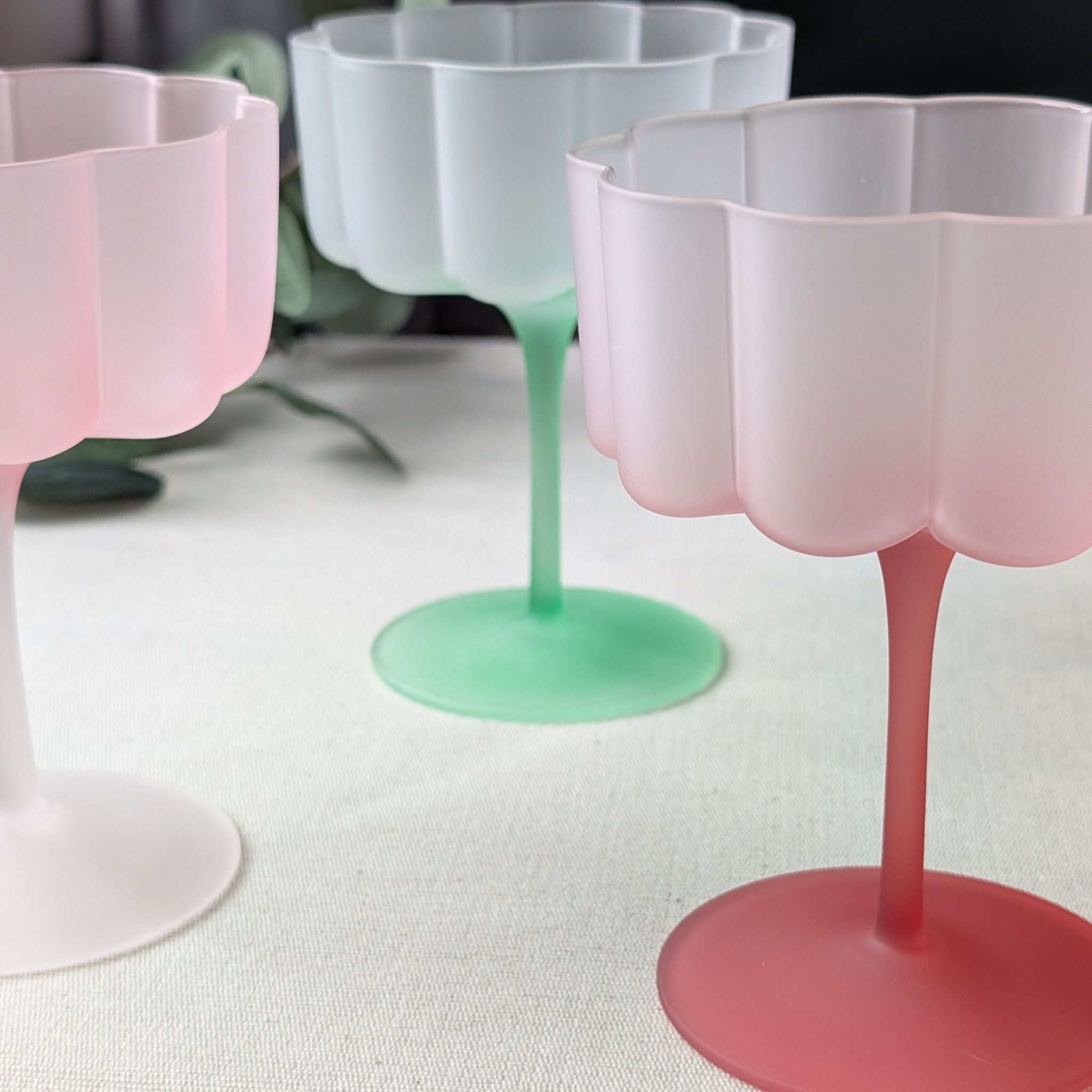Set of pastel flower-shaped scalloped glasses in pink and green, perfect for cocktails, wine, or desserts