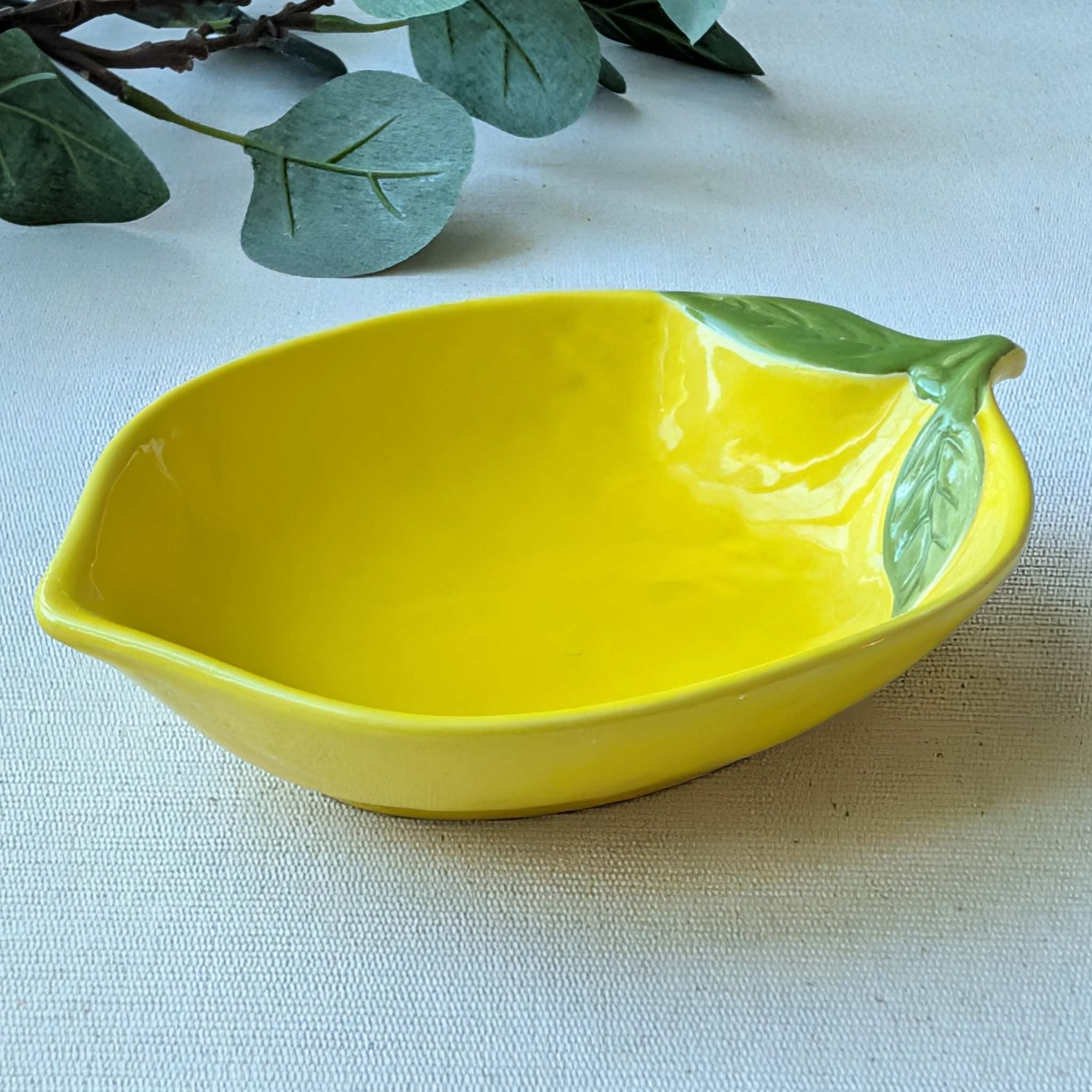 Lemon-shaped yellow ceramic plate with glossy finish and green leaf detail