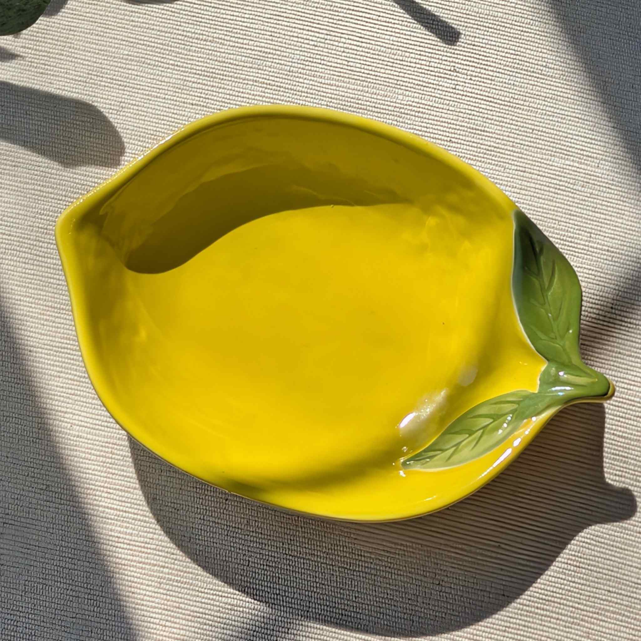 Lemon-shaped yellow ceramic plate with glossy finish and green leaf detail