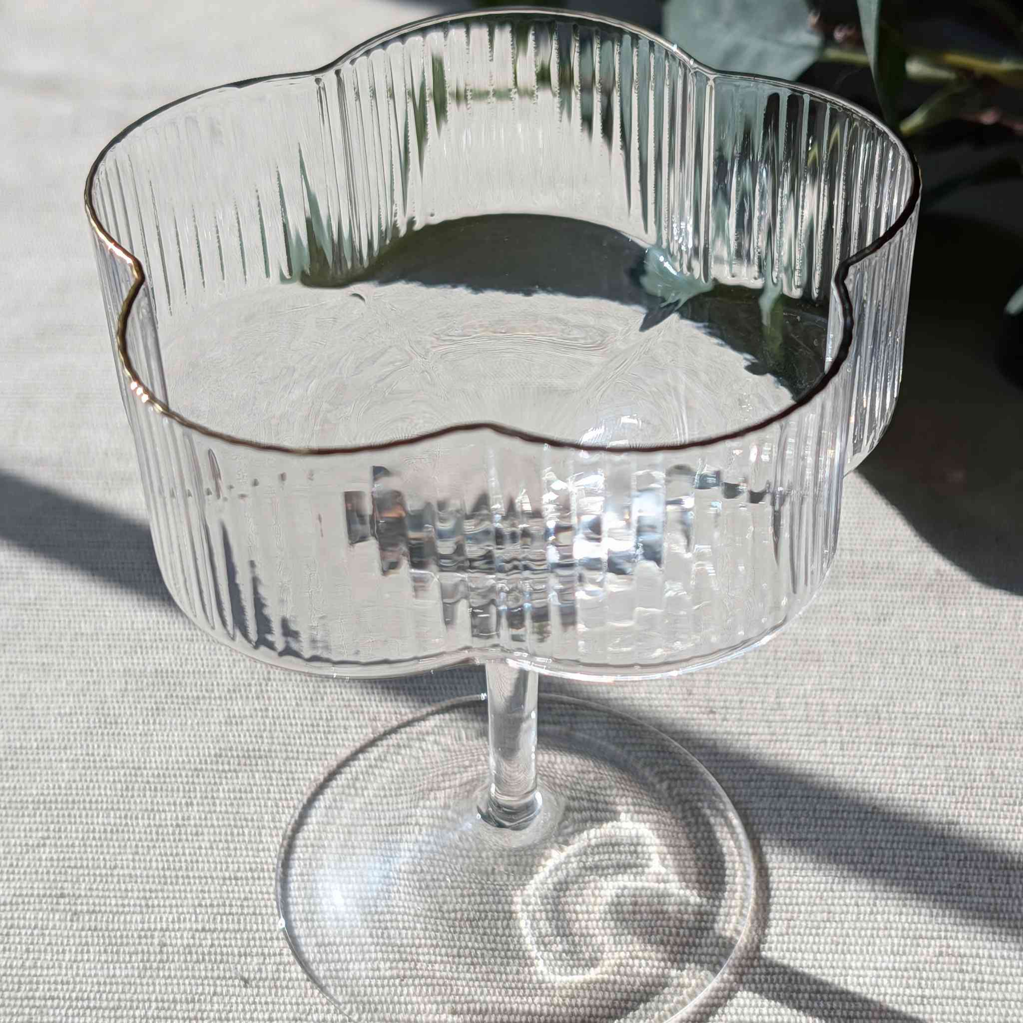 Flower-shaped glass coupe with ribbed design and gold rim, elegant stemmed glassware for cocktails, desserts, or special occasions