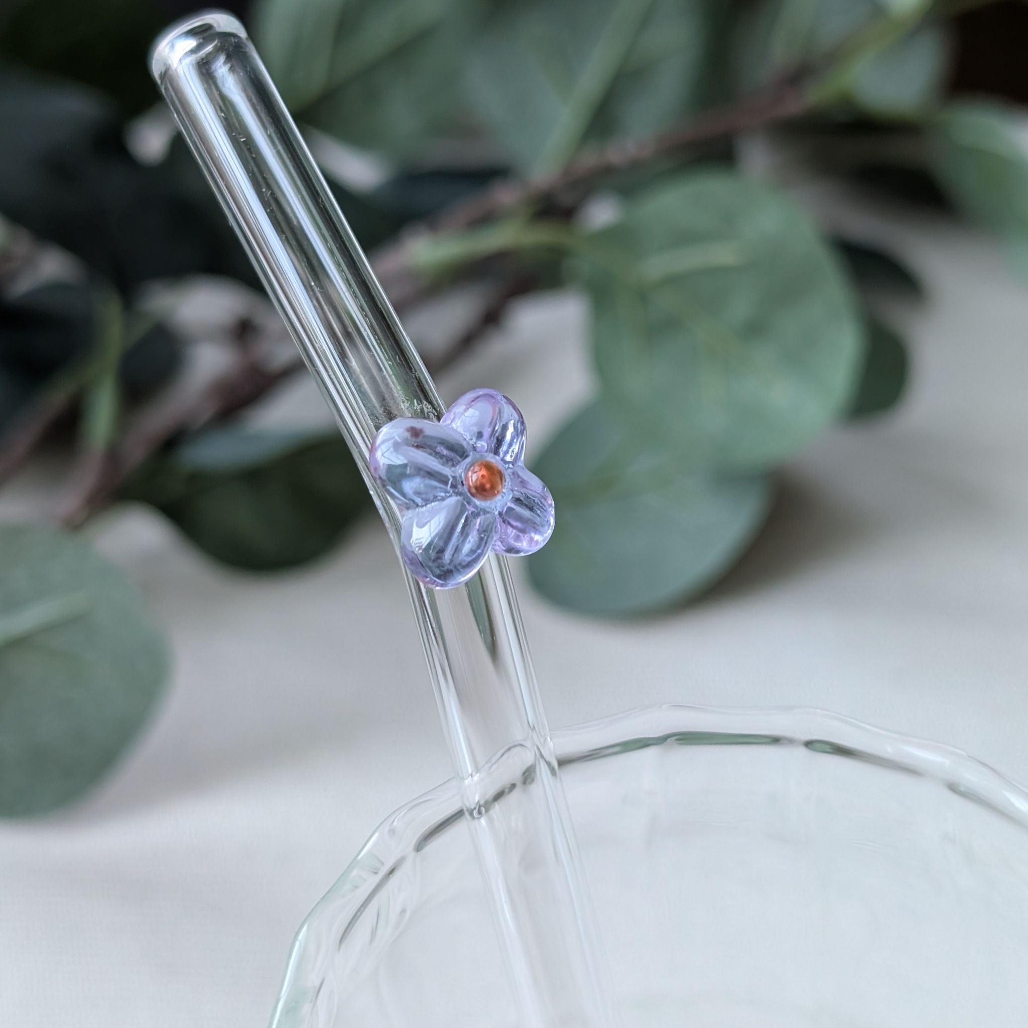 Reusable glass straws adorned with delicate flower detail in purple