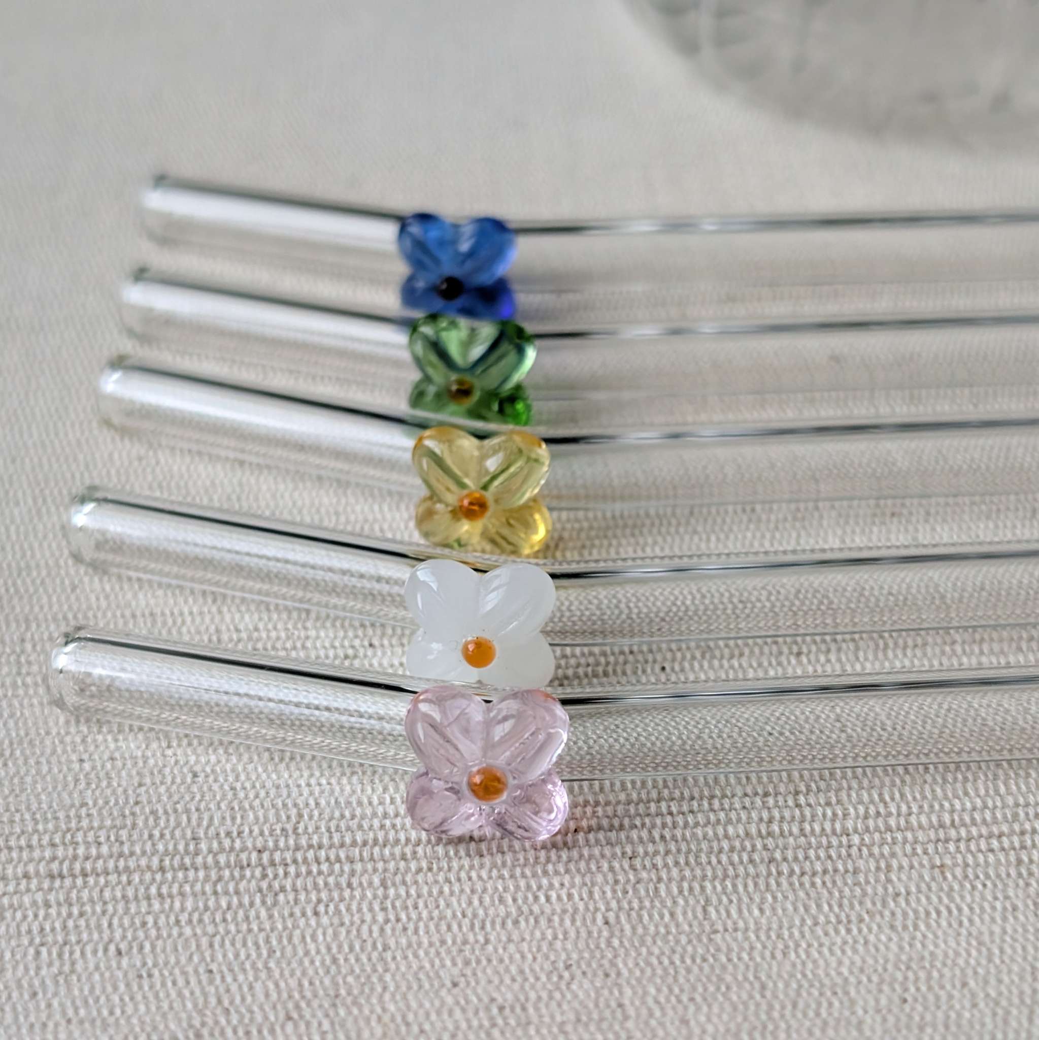 Set of reusable glass straws adorned with delicate flower details in pink, white, yellow, green, and blue