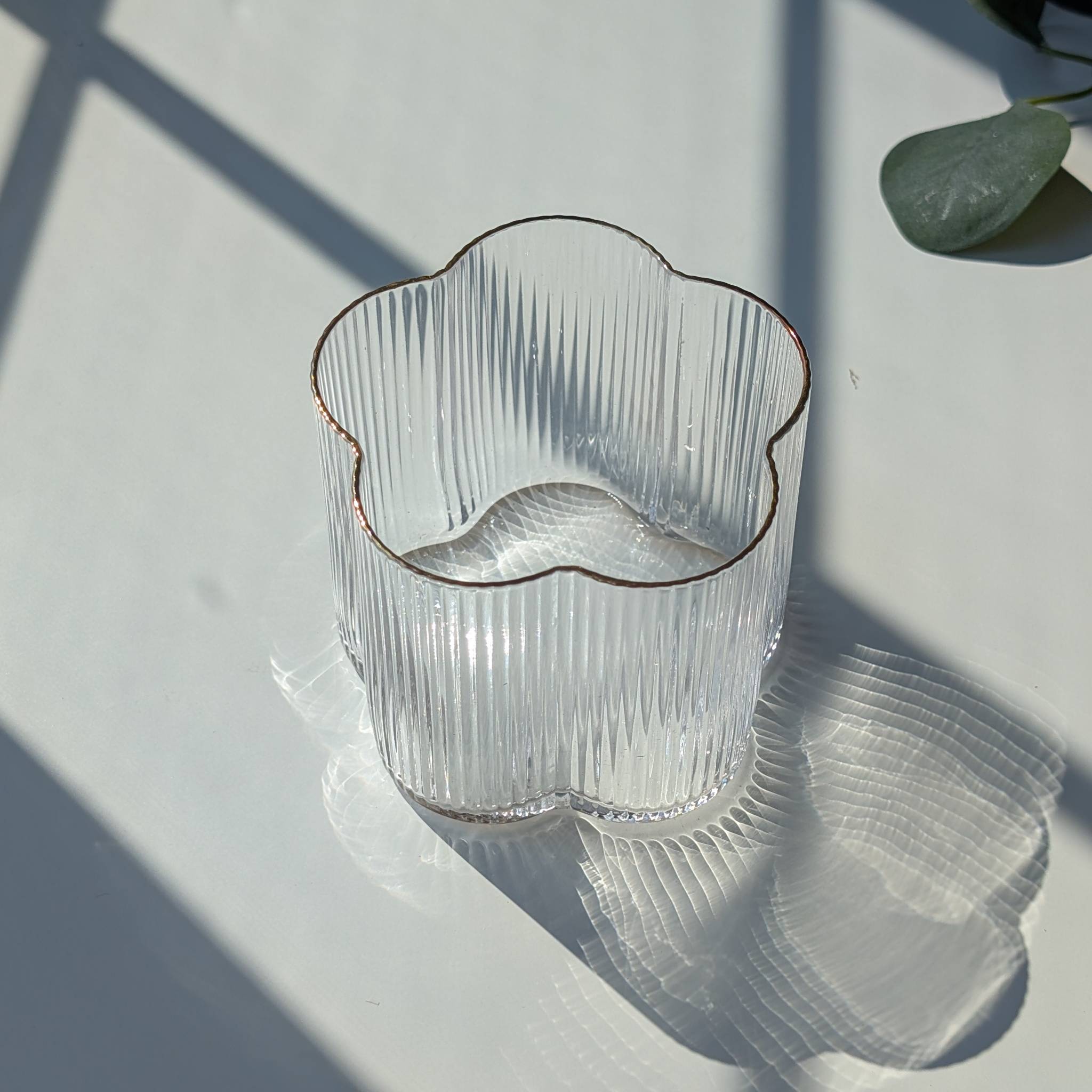 Clear ribbed floral-shaped glass with a delicate gold rim