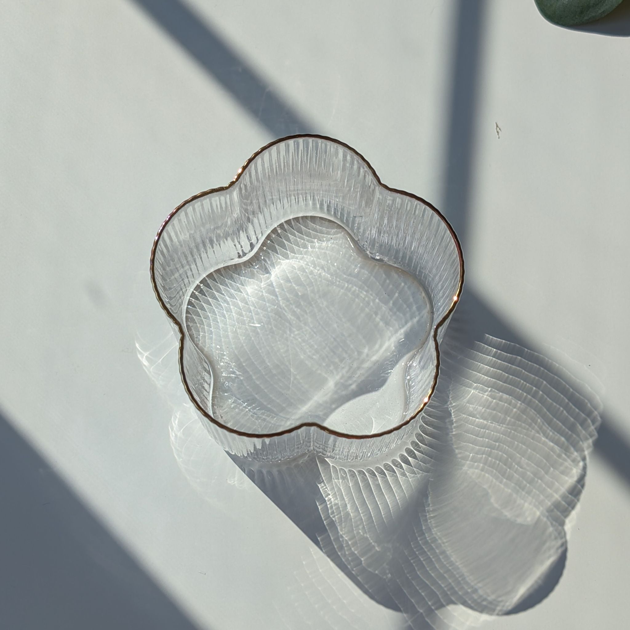 Clear ribbed floral-shaped glass with a delicate gold rim