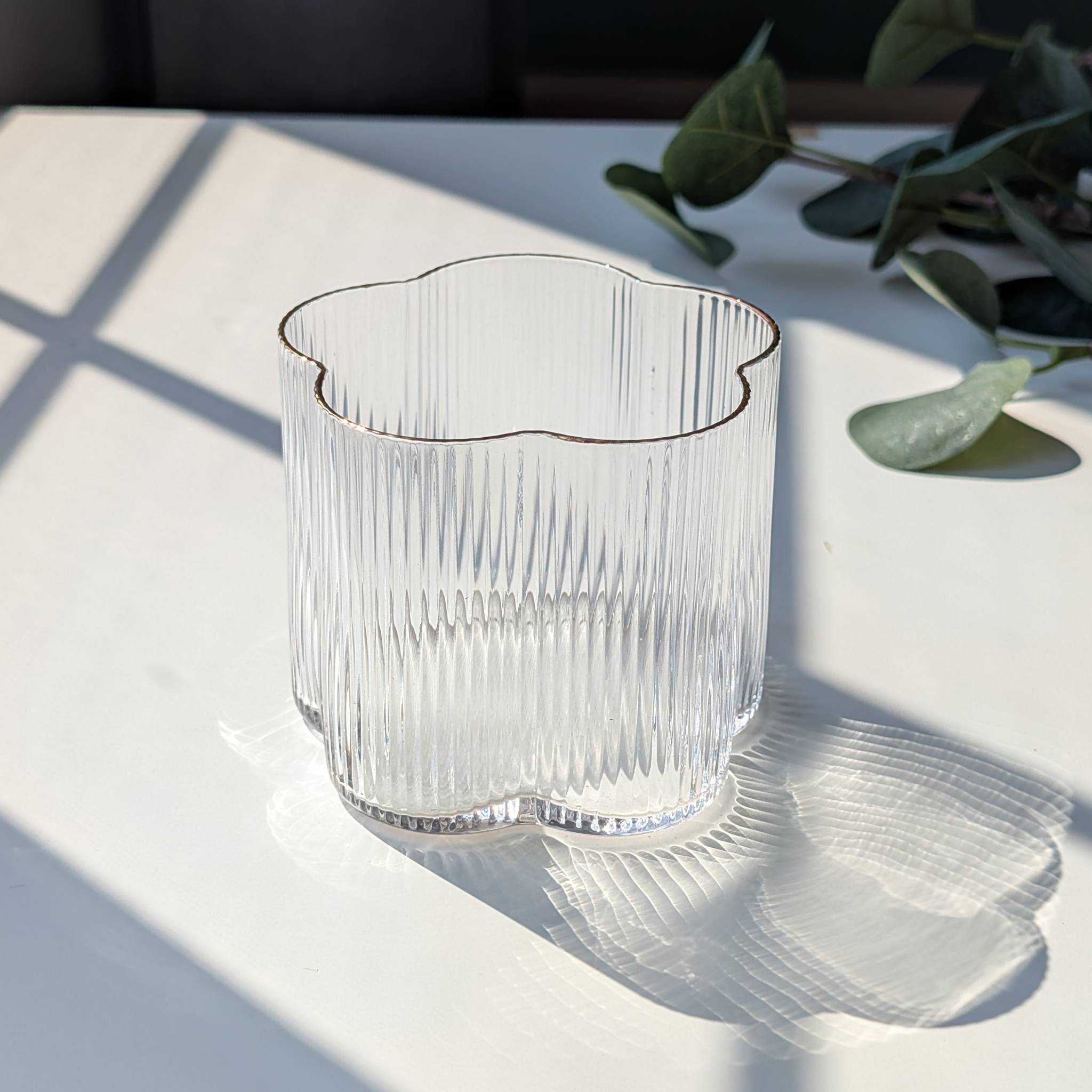 Clear ribbed floral-shaped glass with a delicate gold rim