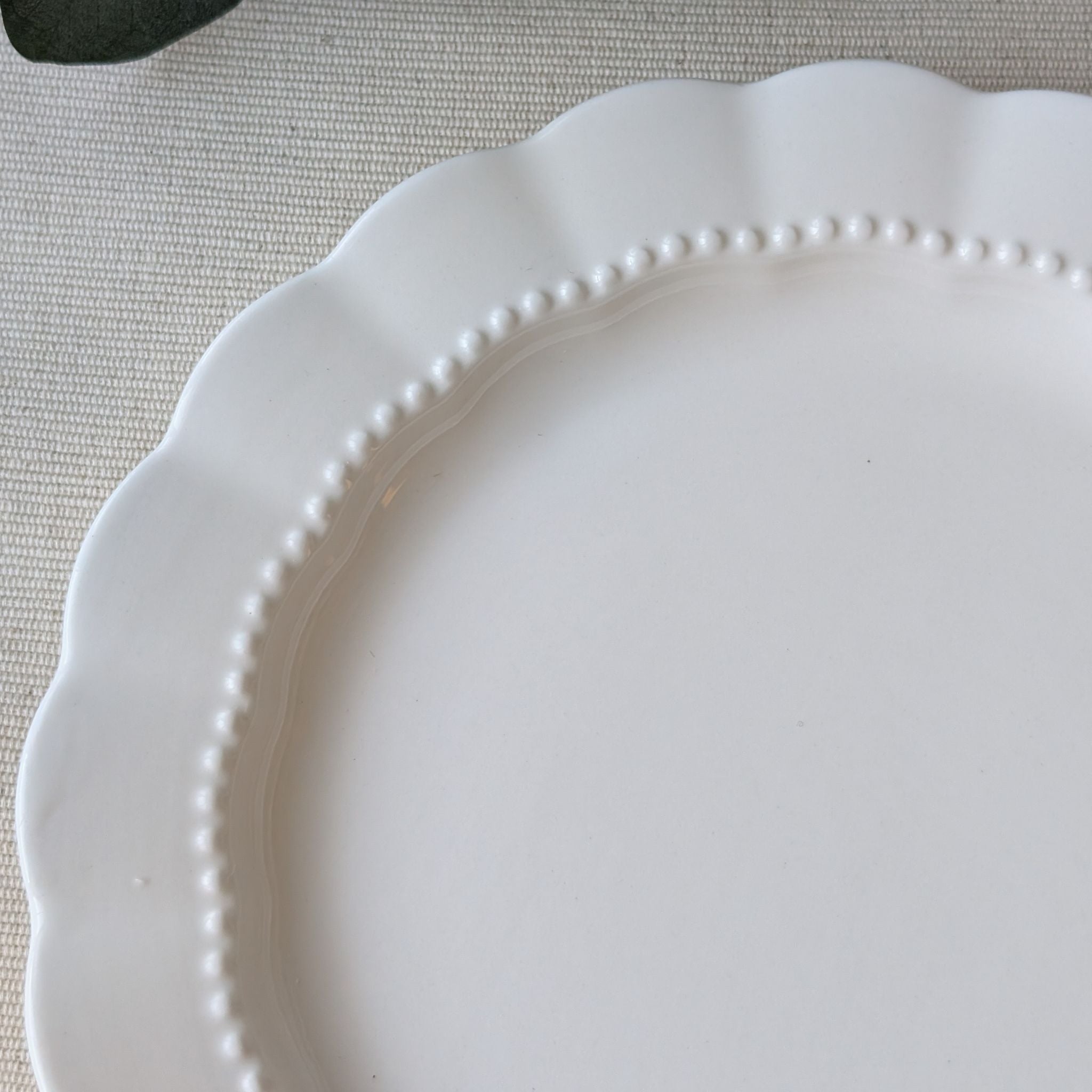 Elegant white scalloped ceramic plate with a delicate beaded rim