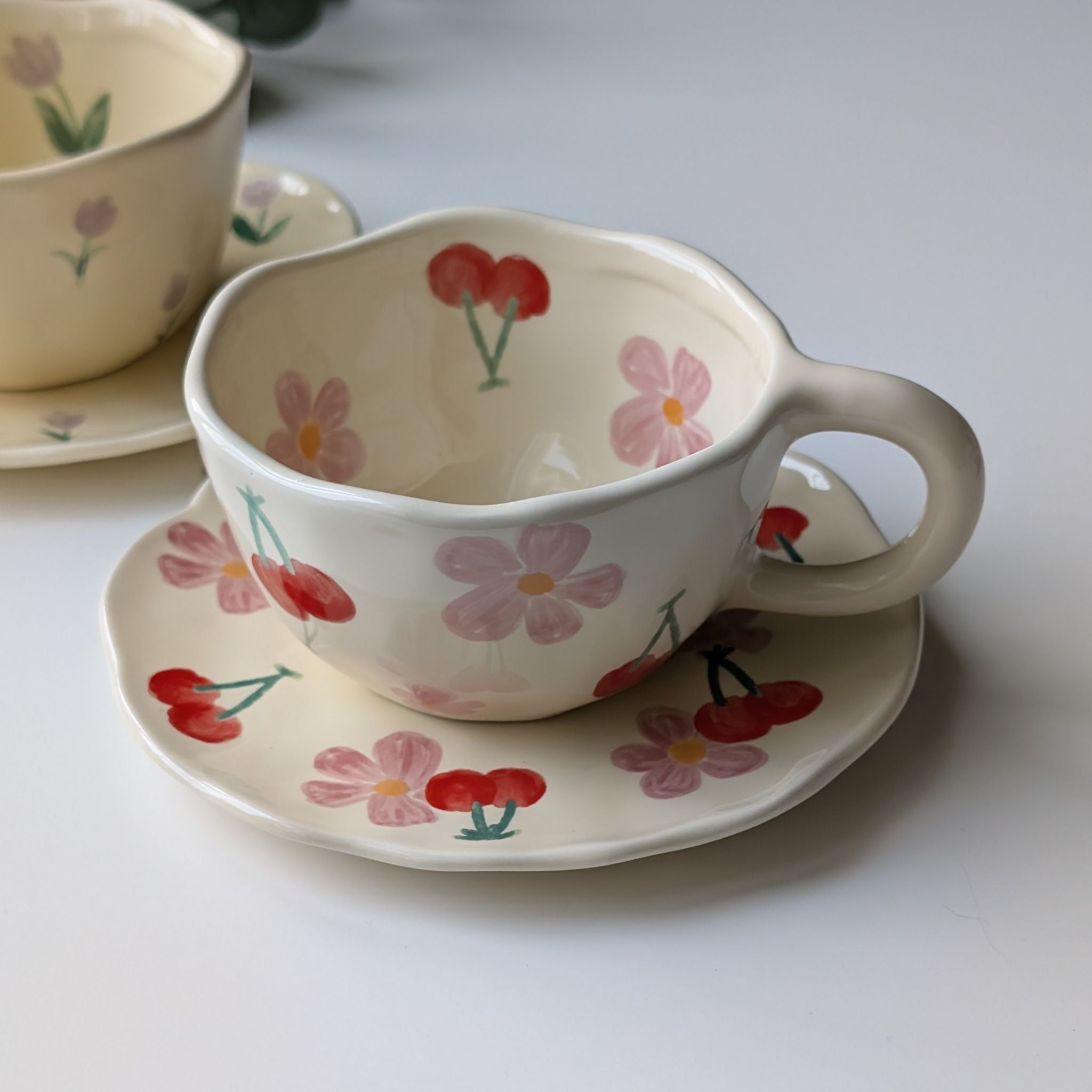 Wavy cream ceramic cup and plate set with floral and cherry design