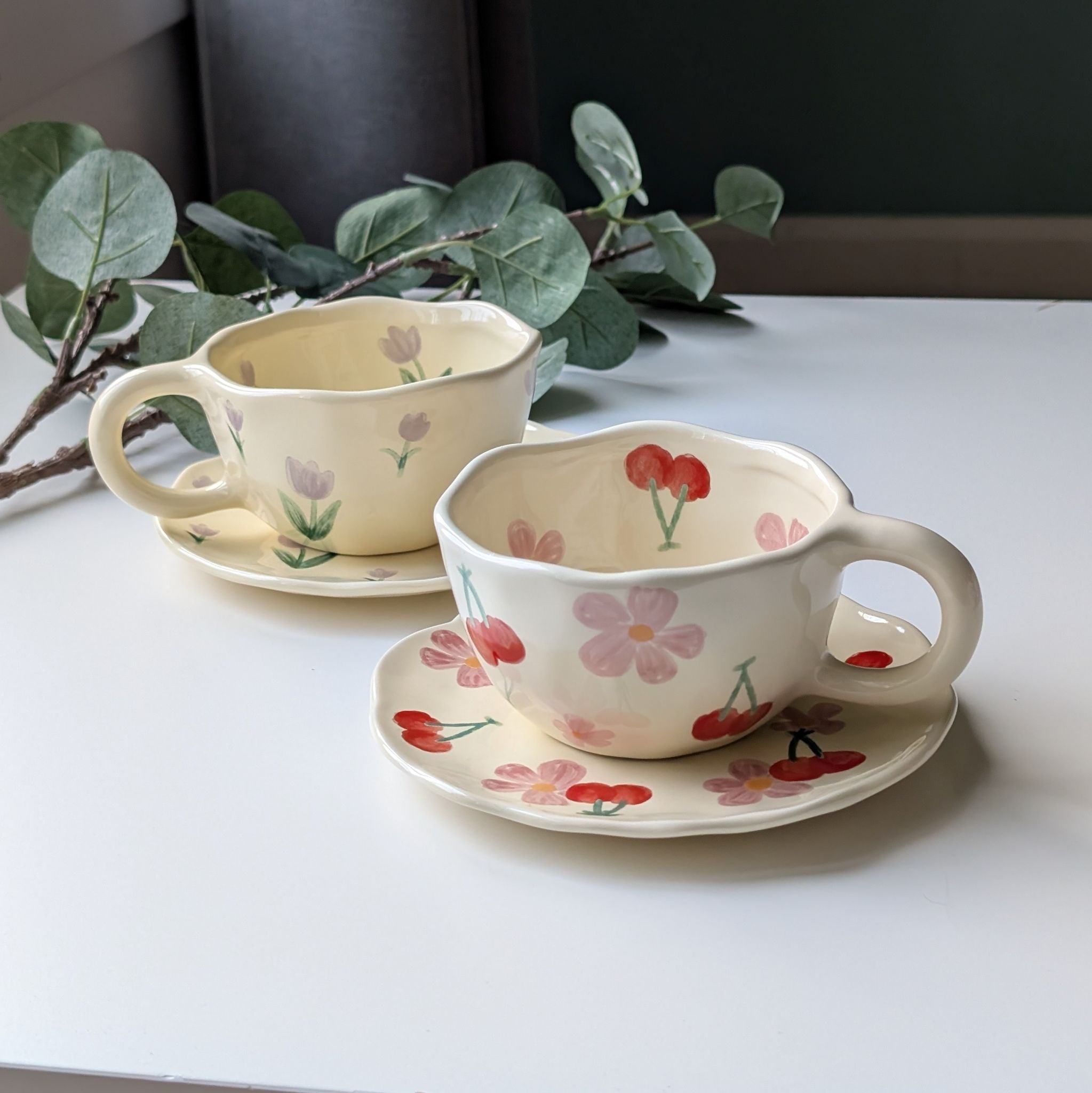Two wavy ceramic cup sets including a plate with floral and cherry designs