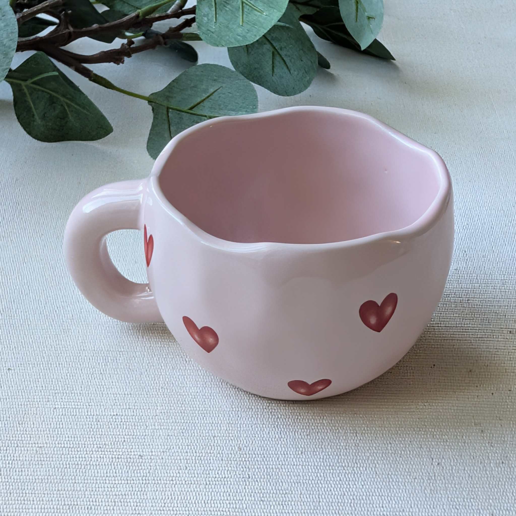 Adorable wavy pink ceramic mug decorated with red hearts — a charming coffee cup or romantic Valentine’s Day gift idea