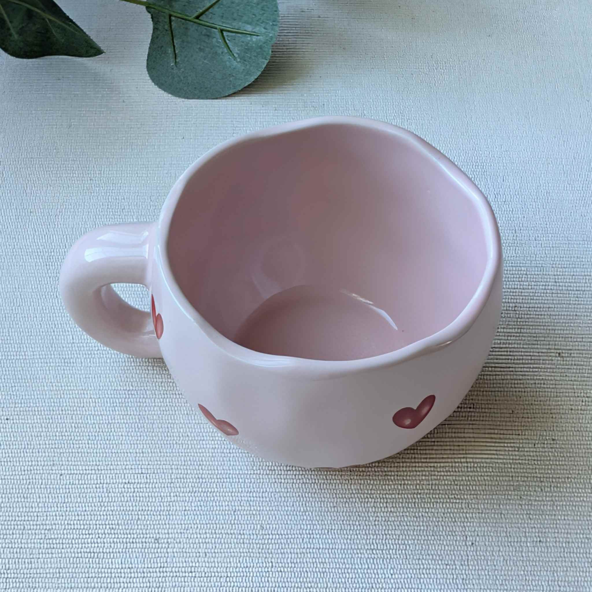 Adorable wavy pink ceramic mug decorated with red hearts — a charming coffee cup or romantic Valentine’s Day gift idea