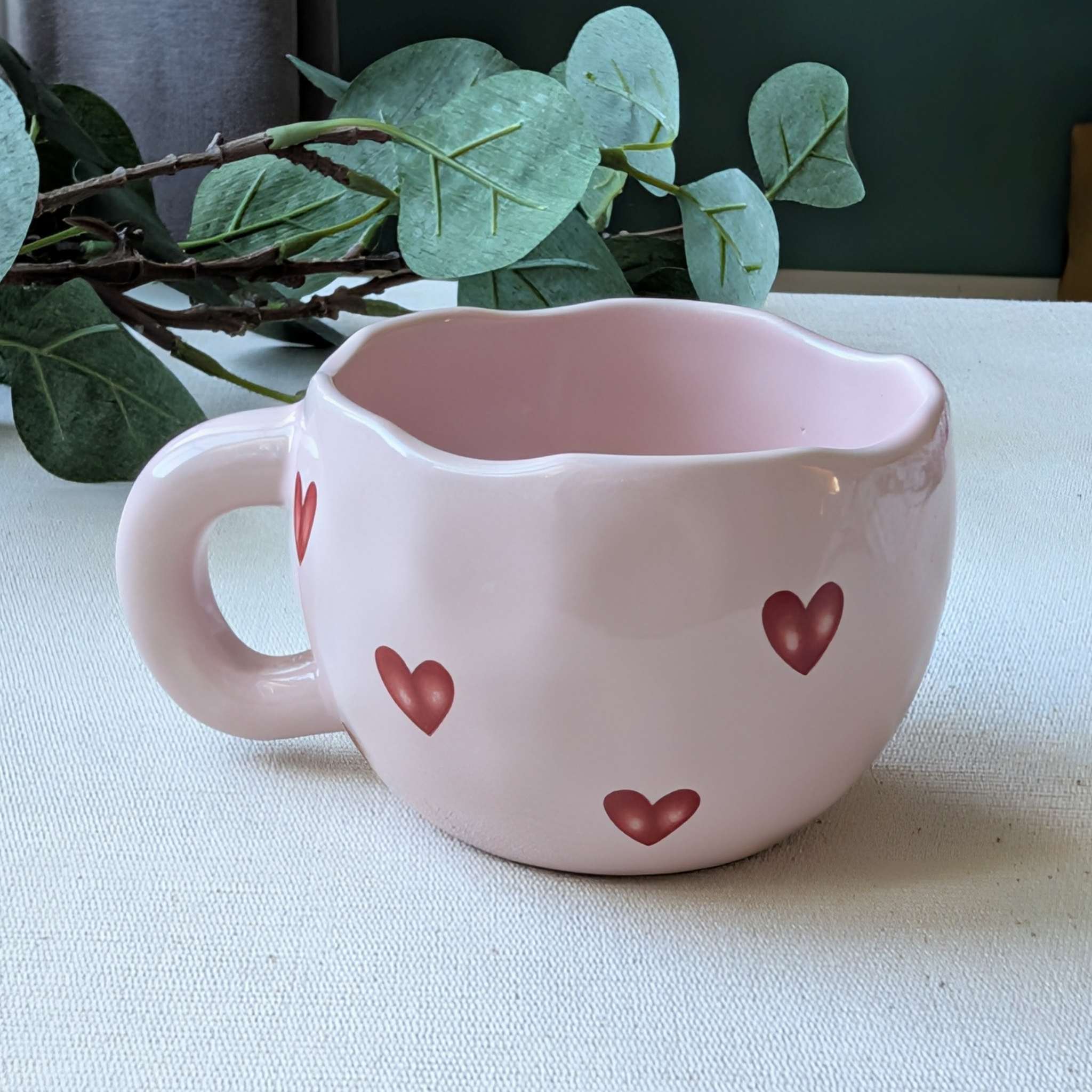 Adorable wavy pink ceramic mug decorated with red hearts — a charming coffee cup or romantic Valentine’s Day gift idea